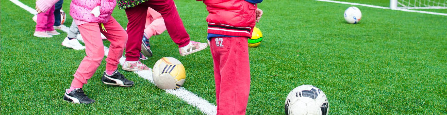 Jambes d'enfants jouant au foot en extérieur, comment aider enfant à bien se développer