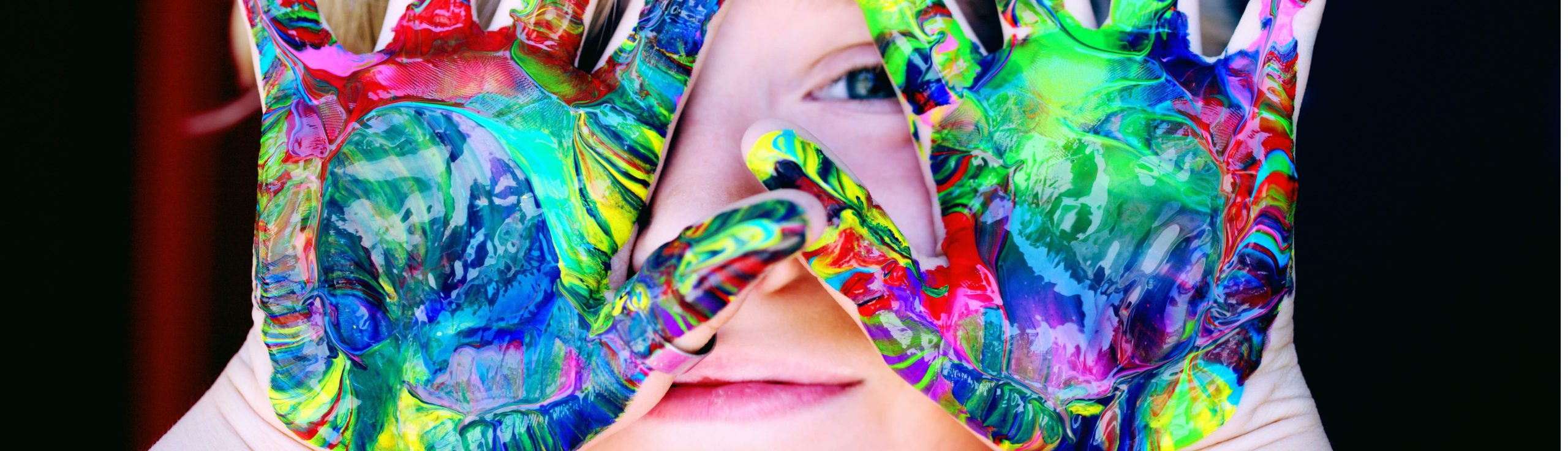Mains d'enfant pleines de peinture devant son visage,  Comment aider enfant à bien se développer