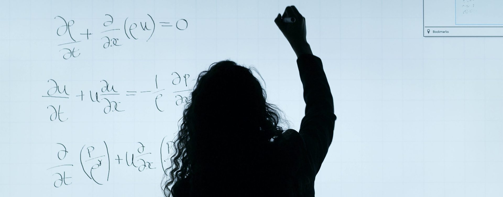 Une femme écrit une formule sur un tableau blanc - comment orienter les petites filles vers la science