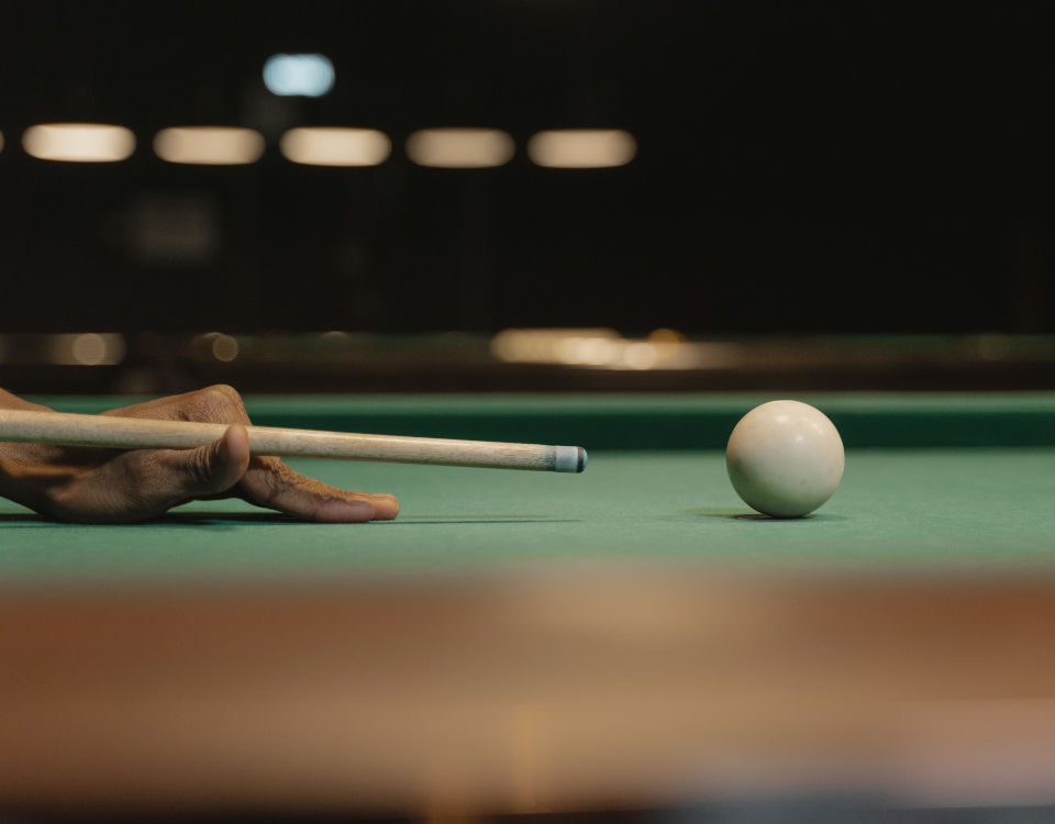 Zoom sur joueur frappant la bille de choc au billard.